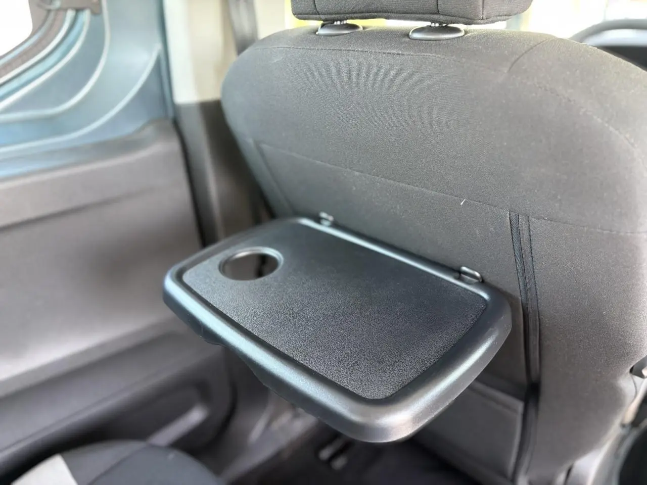 Détail de la tablette aviation rabattable noire sur le dossier du siège avant du Citroën Berlingo ë-136 Bleu Kiama.