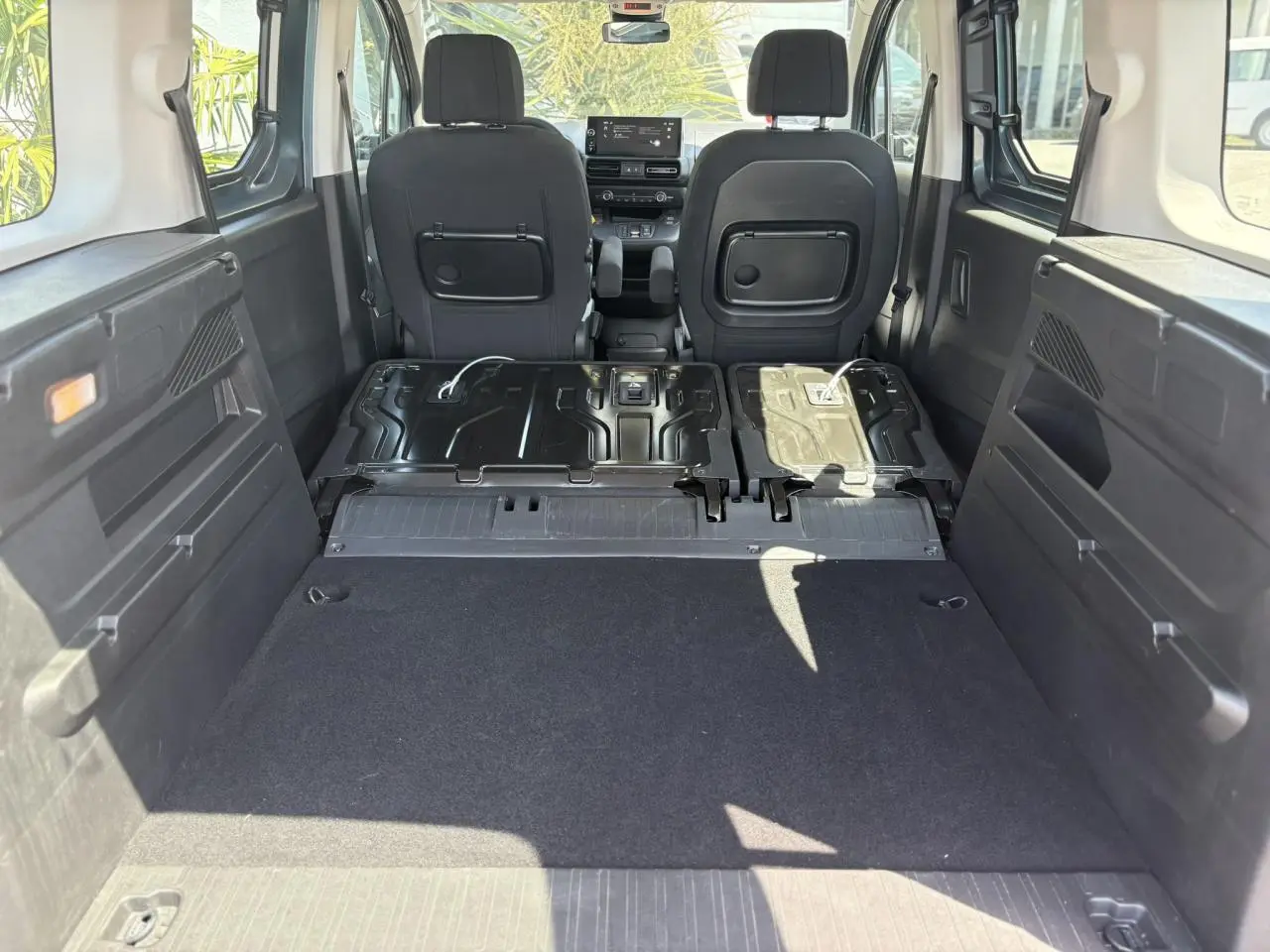Vue intérieure arrière du Citroën Berlingo ë-136 avec banquette rabattue et plancher de coffre plat, ambiance Urban Grey.