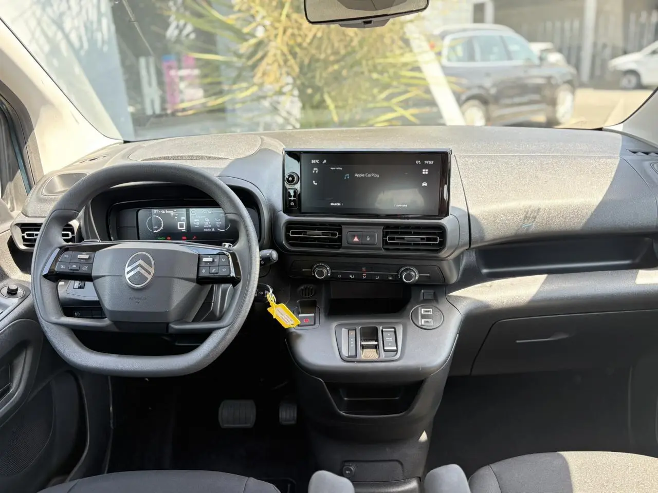 Vue intérieure frontale du tableau de bord du Citroën Berlingo ë-136, avec écran tactile et volant multifonction.