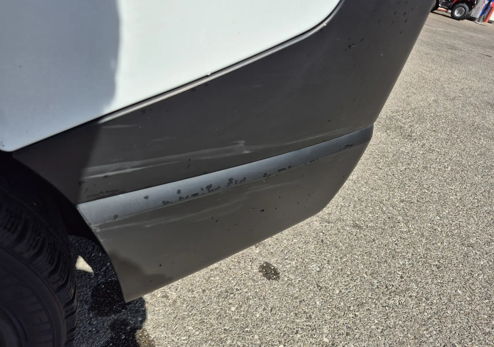 Gros plan sur l'angle arrière droit du Nissan Primastar blanc, montrant un pare-chocs noir avec des traces d'usure.
