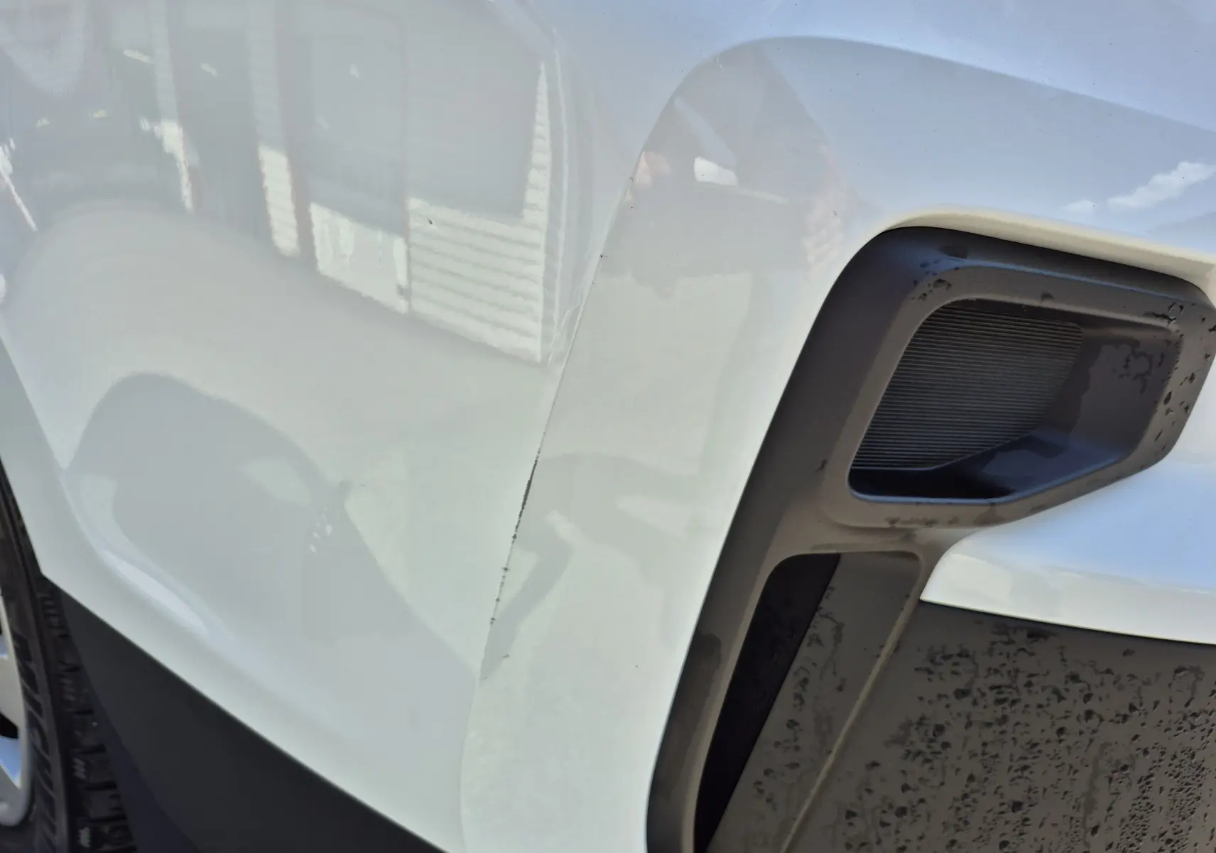 Gros plan sur l’aile avant droite blanche du Nissan Primastar, mettant en valeur la prise d’air noire et la carrosserie brillante.