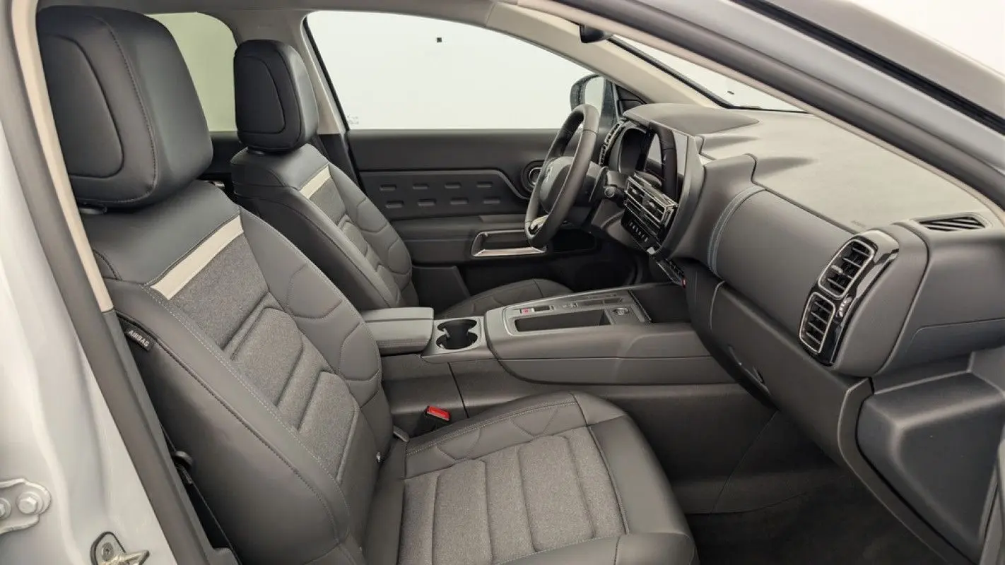 Vue intérieure côté conducteur du Citroën C5 Aircross blanc Okenite, sièges en cuir et tissu gris avec tableau de bord moderne.