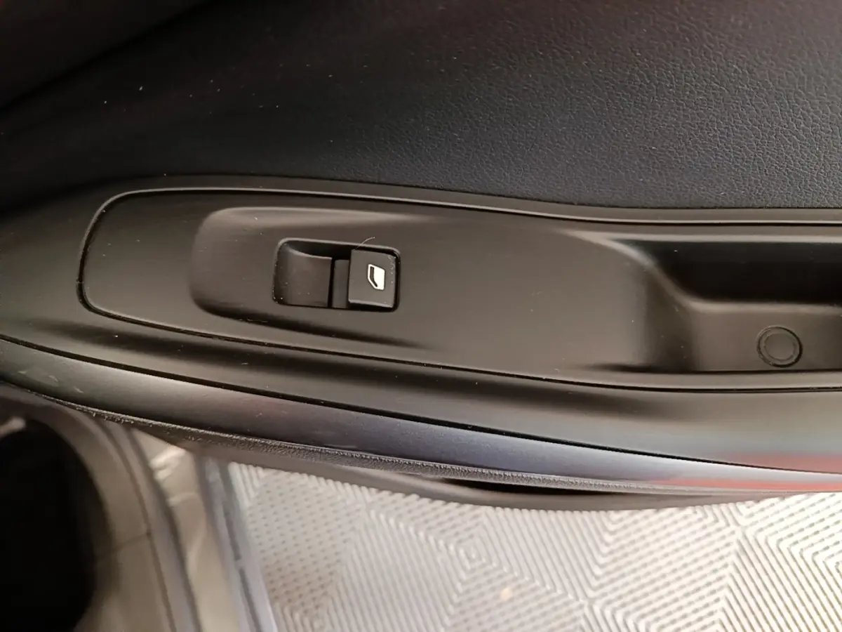 Gros plan sur le bouton de lève-vitre électrique côté conducteur de l’Opel Grandland X gris foncé.