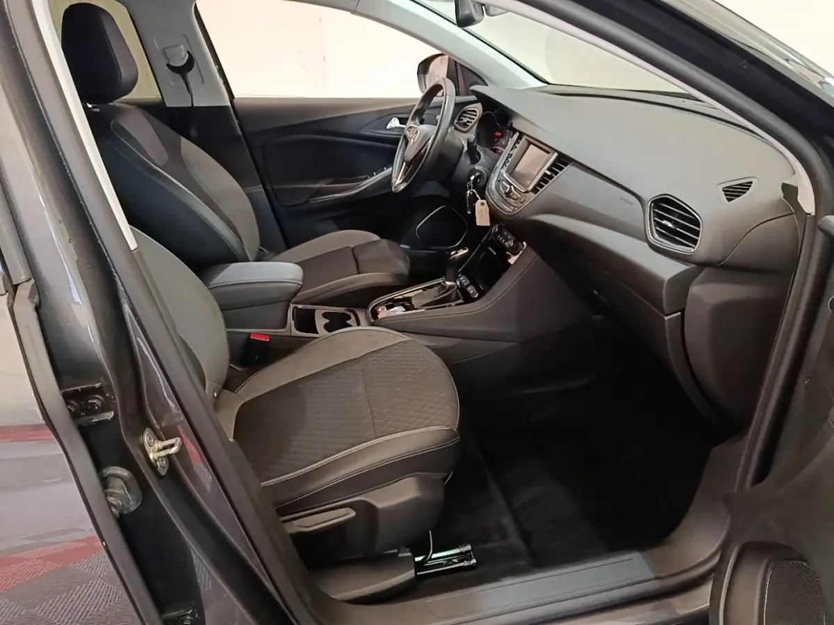 Intérieur avant droit de l’Opel Grandland X gris foncé, montrant sièges tissu, volant multifonctions et tableau de bord moderne.