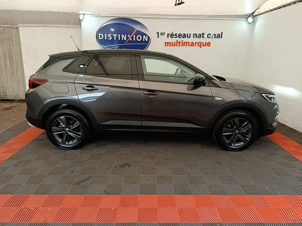 Vue latérale droite d'un Opel Grandland X gris foncé garé en intérieur avec jantes alliage noires.