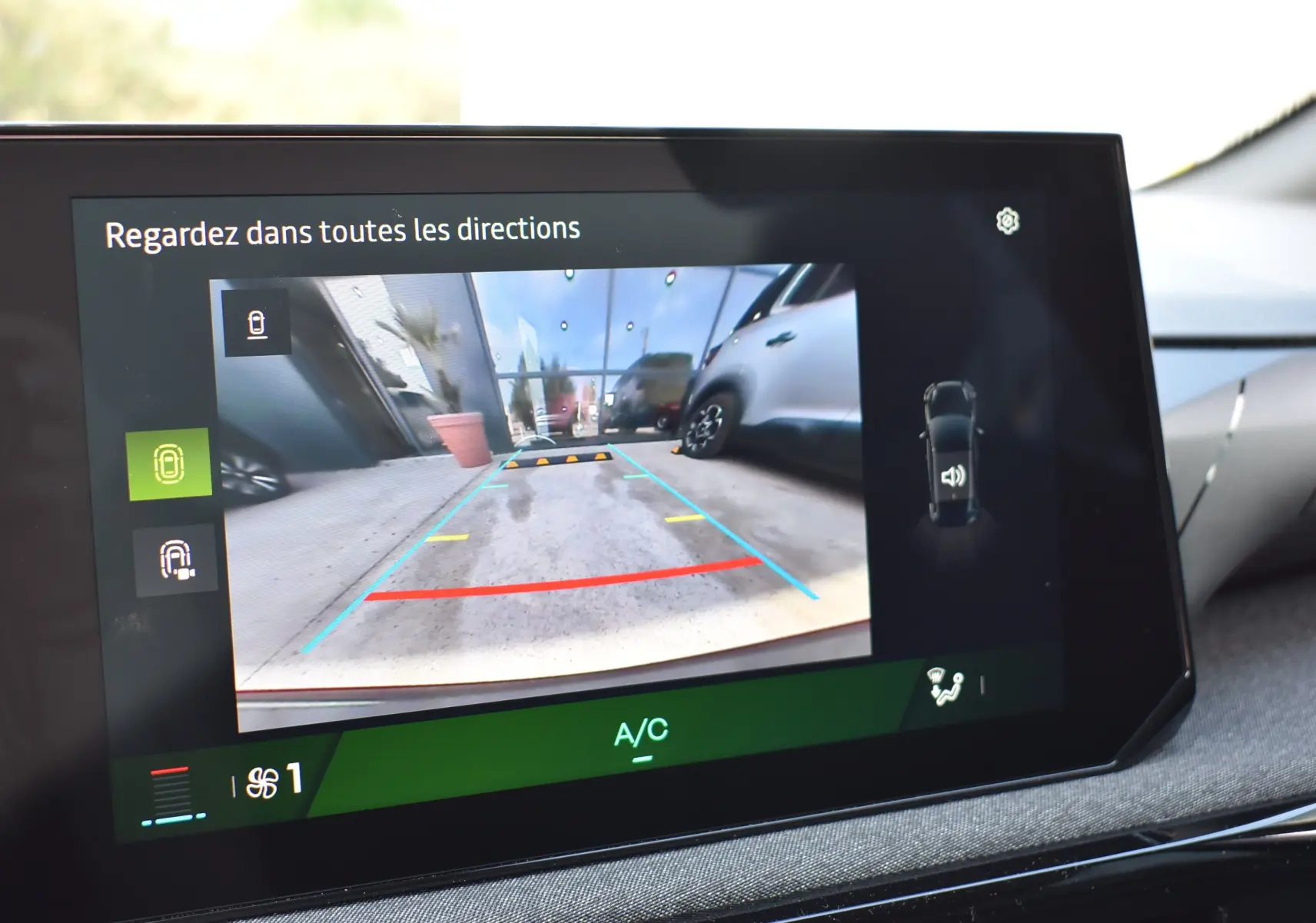 Écran tactile intérieur montrant la caméra de recul avec vue arrière du parking, tableau de bord gris.