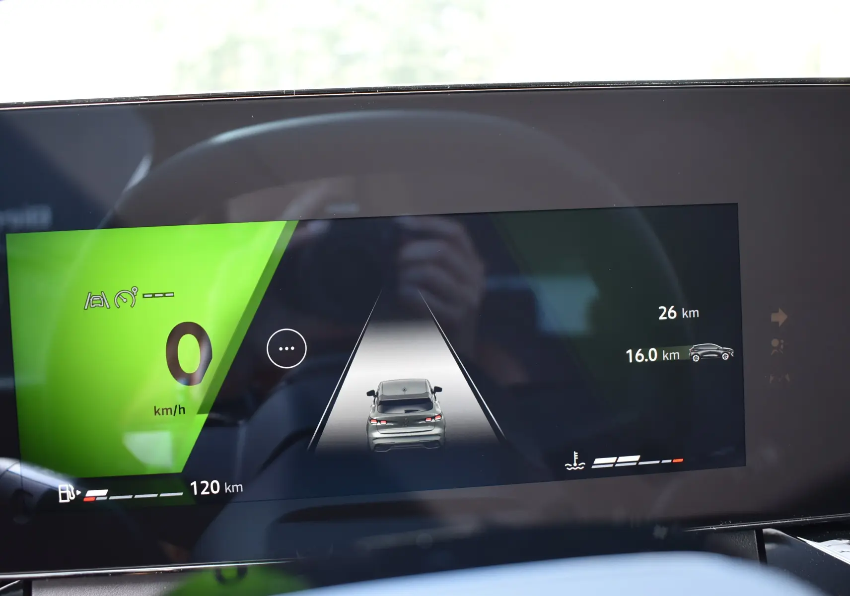 Tableau de bord numérique de Renault Clio VI affichant la vitesse à 0 km/h et une voiture grise vue de dos.