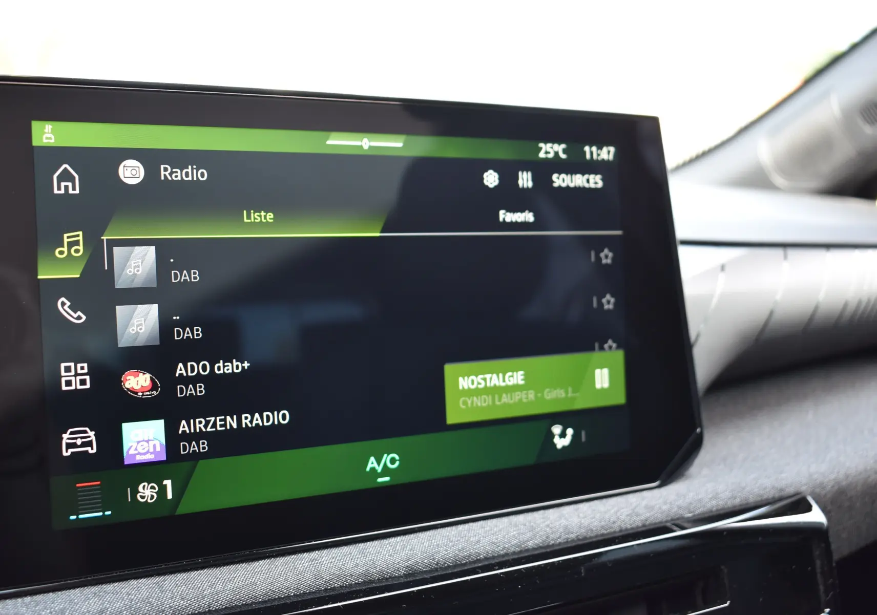 Écran tactile du système audio de la Renault Clio VI gris schiste, affichant les stations radio DAB et la chanson Nostalgie.