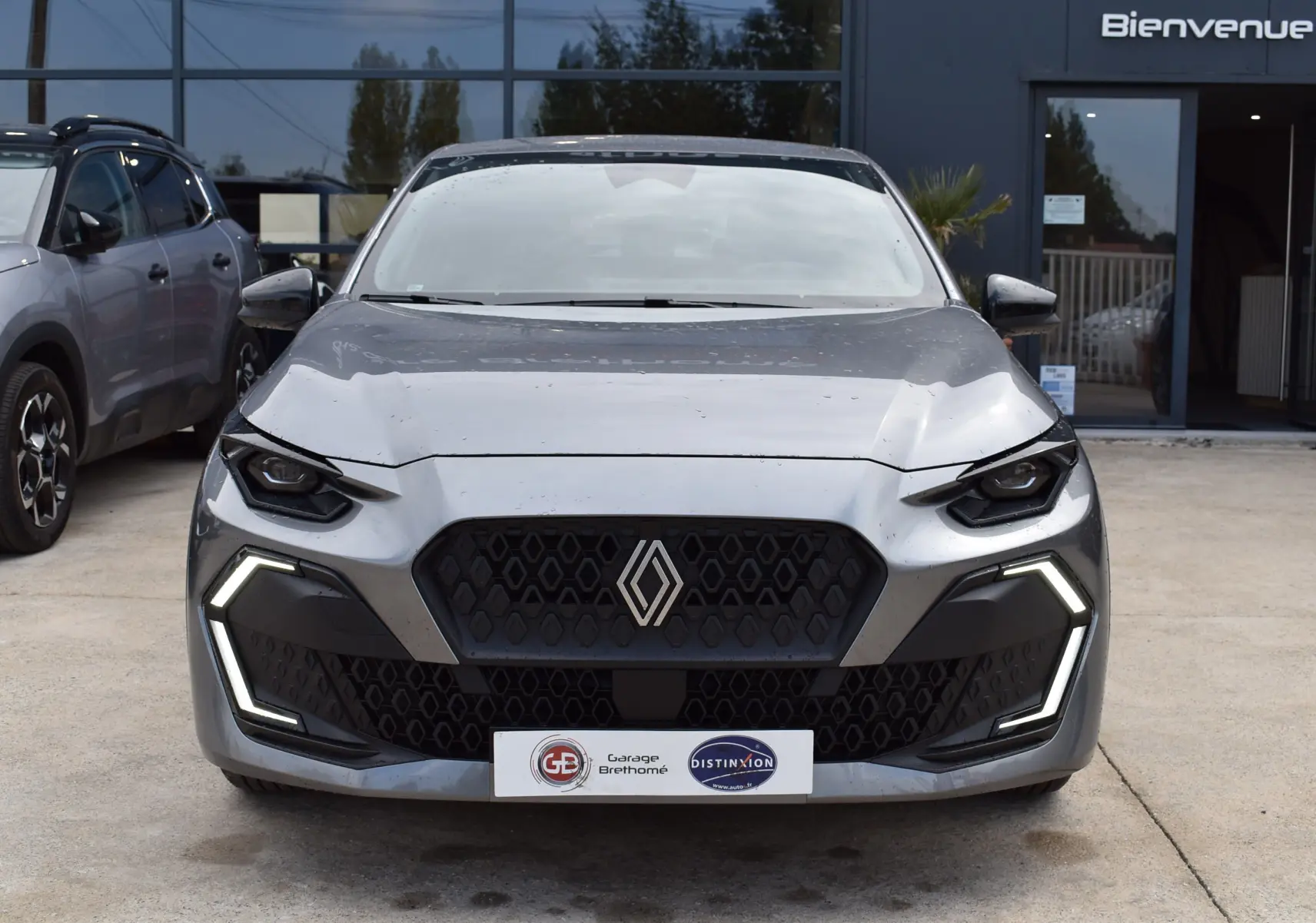 Vue avant d'une Renault Clio VI gris schiste avec feux LED en forme de C et calandre noire hexagonale.