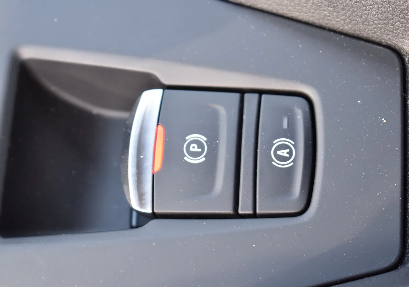 Gros plan sur les boutons de frein à main électrique et arrêt/démarrage automatique dans une Renault Clio VI gris schiste.