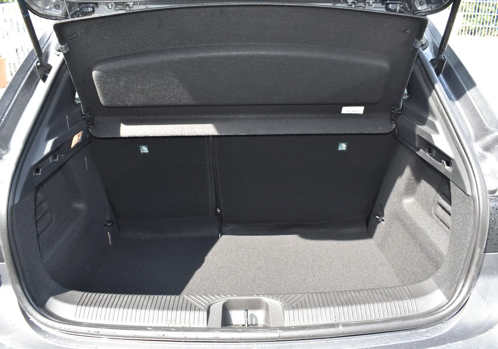 Coffre ouvert vu de l'arrière d'une Renault Clio VI gris schiste, montrant le cache-bagages rigide et l'espace de chargement.