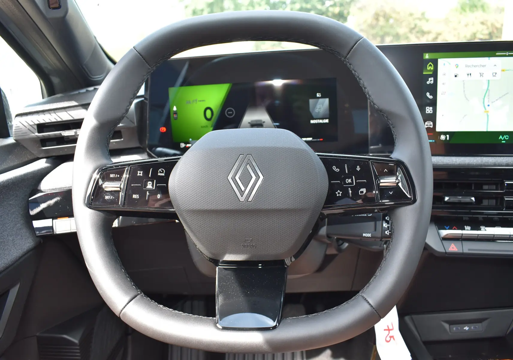 Vue rapprochée du volant multifonctions noir de la Renault Clio VI avec tableau de bord numérique et écran tactile.