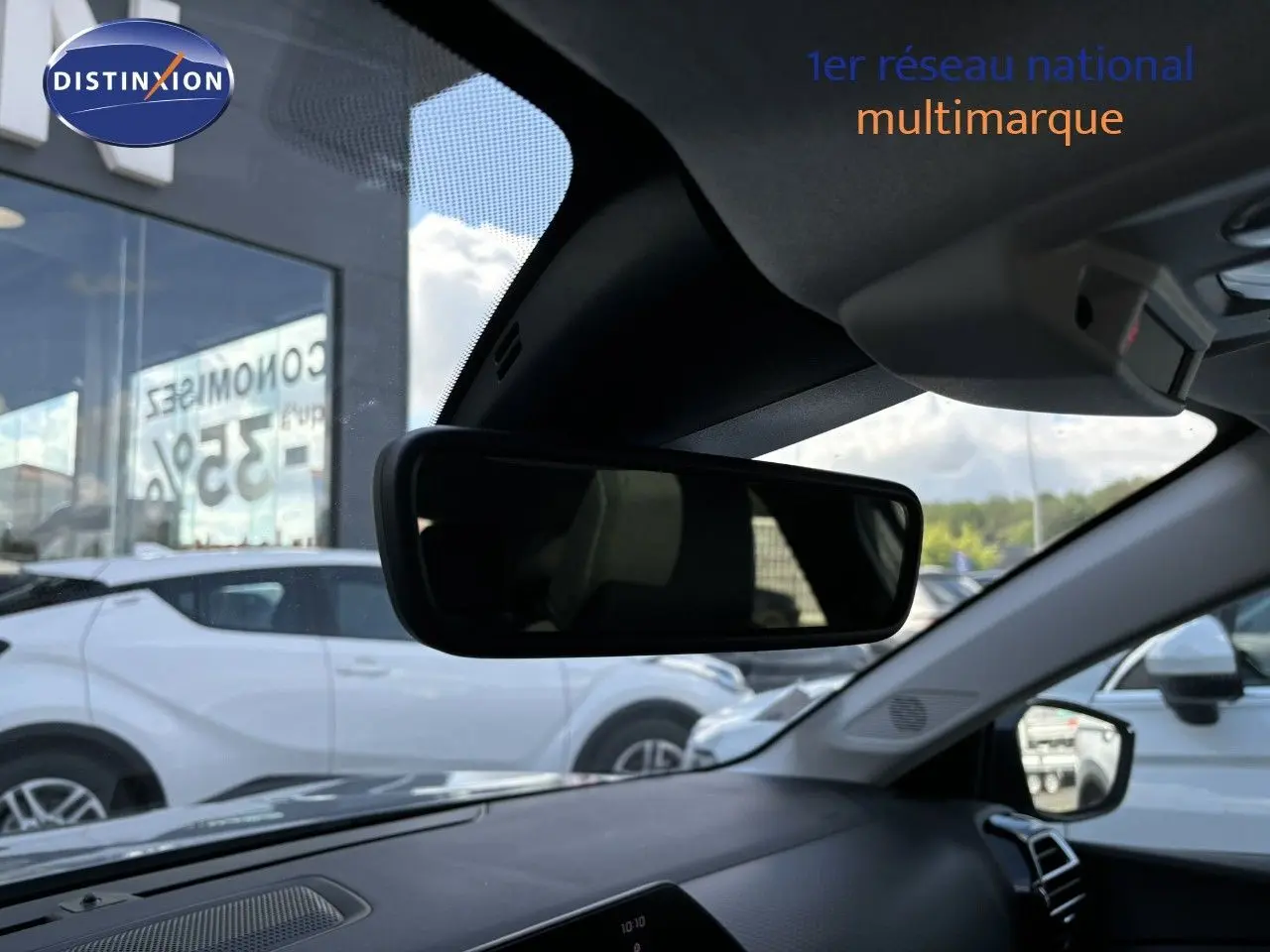 Vue intérieure du rétroviseur central d'une Citroën C4 gris Artense, avec tableau de bord et extérieur en arrière-plan.