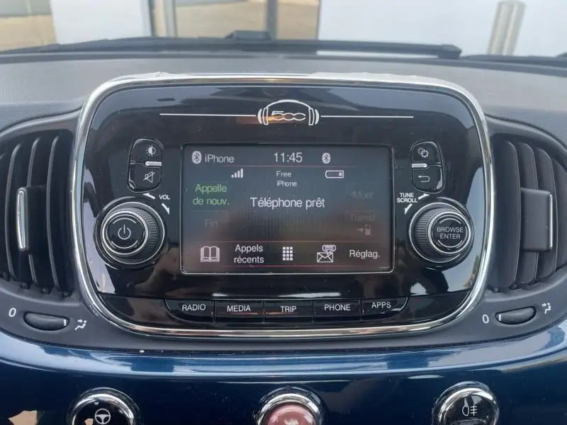 Vue rapprochée du tableau de bord bleu foncé métallisé d'une Fiat 500 avec écran tactile et commandes multimédia visibles.