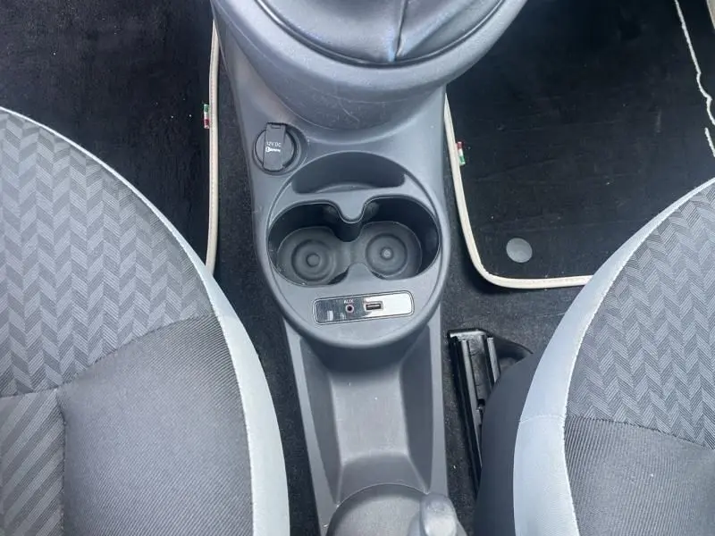 Vue plongeante sur la console centrale de la Fiat 500 diesel 2016, avec porte-gobelets et prise auxiliaire USB.