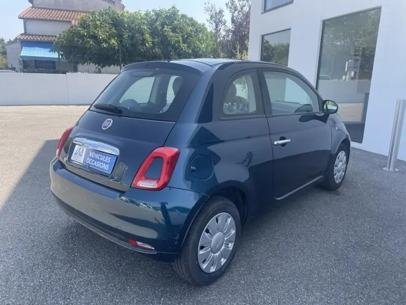 Vue 3/4 arrière droite d'une FIAT 500 bleu foncé métallisé de 2016, compacte et élégante, stationnée sur un parking extérieur.