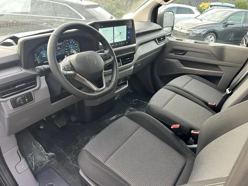 Vue intérieure côté conducteur du Volkswagen Transporter Procab gris 2025, avec tableau de bord numérique et écran tactile central.