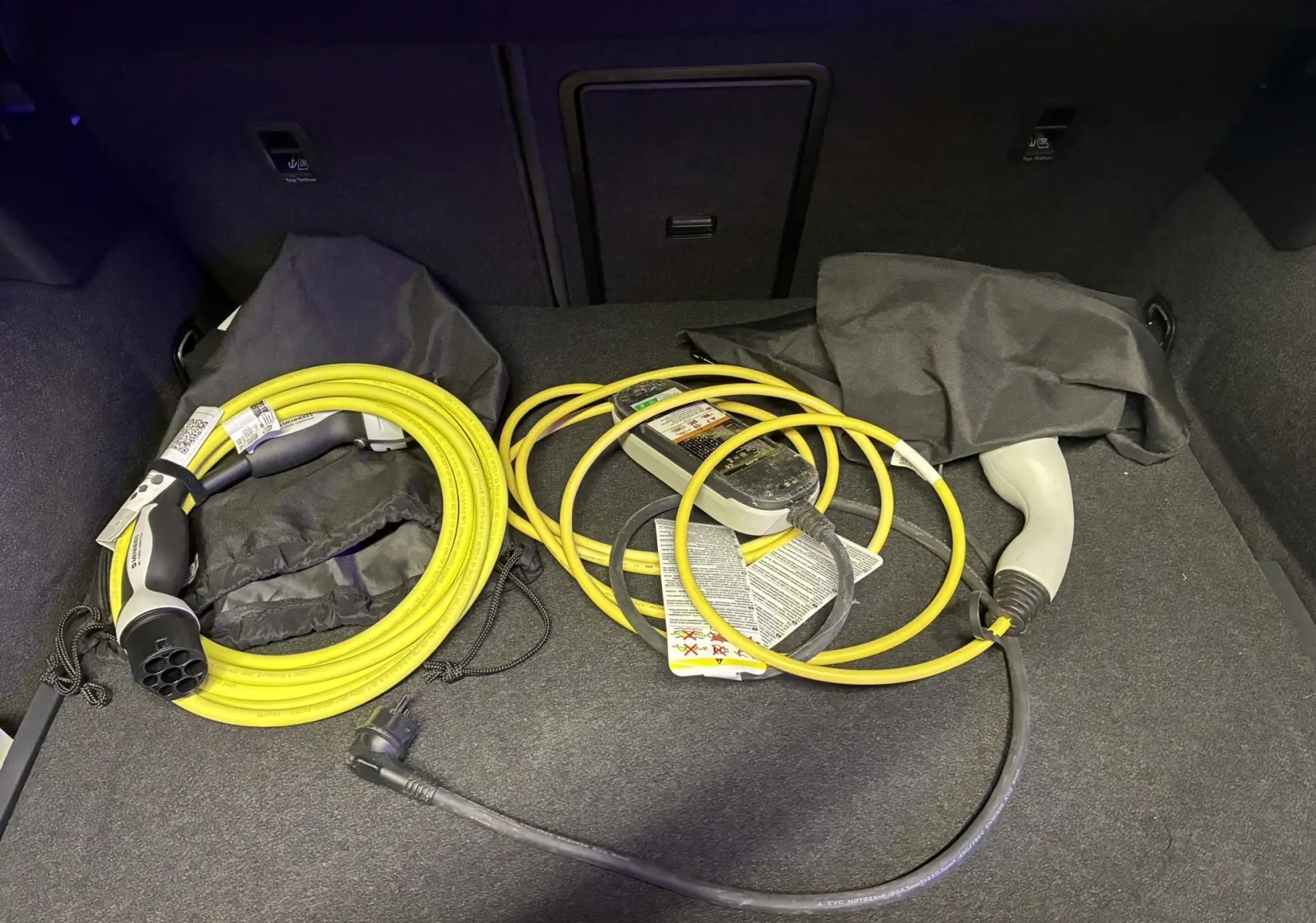 Coffre d’un CUPRA Formentor gris 2023 montrant les câbles de recharge jaune et noir pour hybride rechargeable.