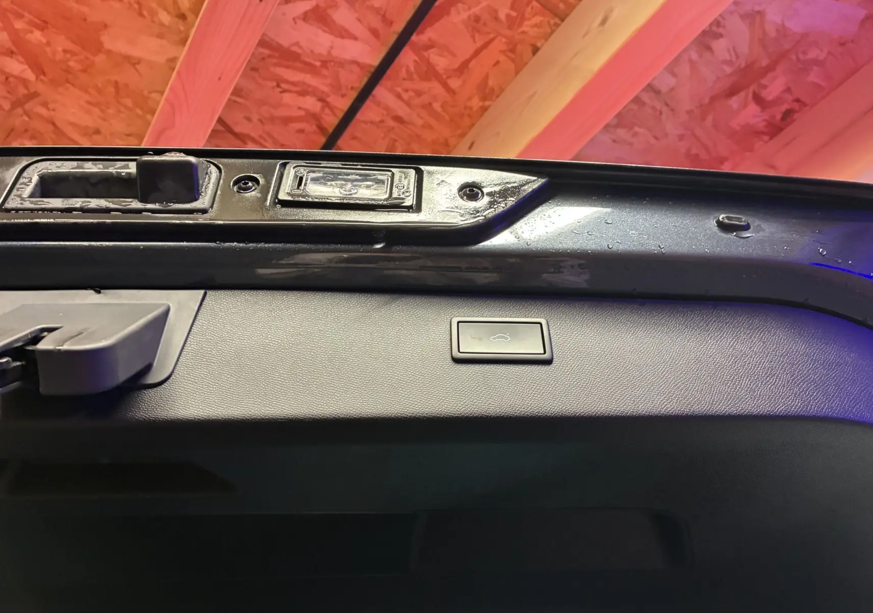 Bouton d'ouverture électrique du coffre sur la partie intérieure de la porte arrière d'un CUPRA Formentor gris.