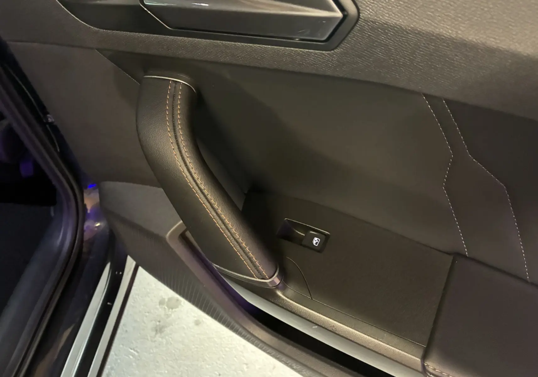Détail de la poignée intérieure en cuir noir avec surpiqûres marron sur la porte côté gauche du CUPRA Formentor gris 2023.