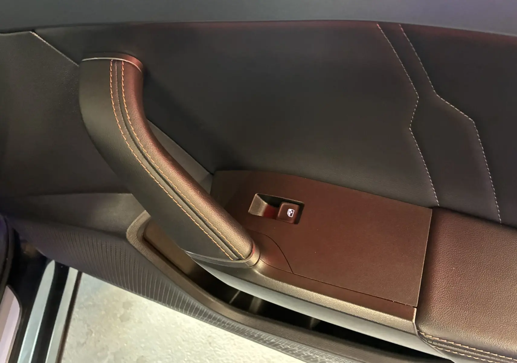 Gros plan sur la poignée de porte intérieure en cuir noir avec surpiqûres orange du CUPRA Formentor gris 2023.