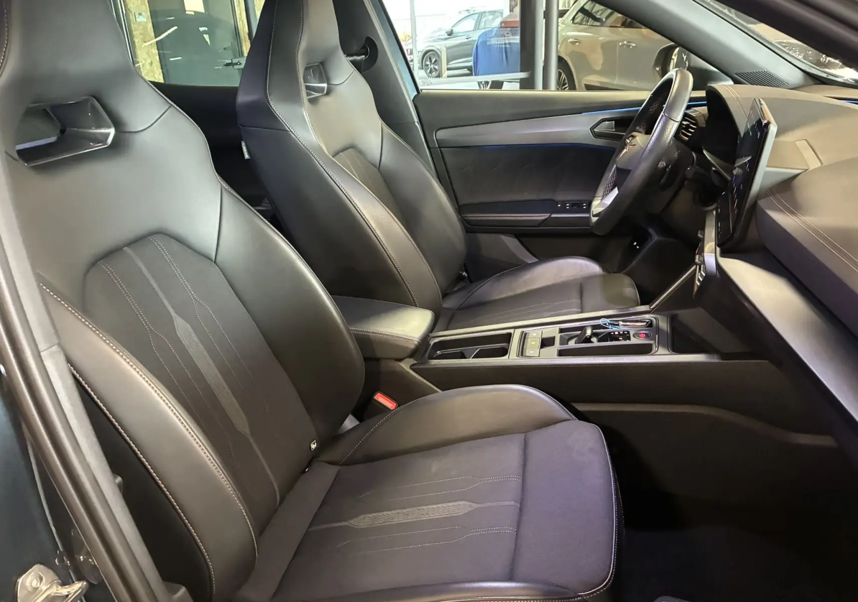 Vue intérieure côté conducteur de la CUPRA Formentor 1.4 e-Hybrid 2023 avec sièges cuir noirs et tableau de bord moderne.