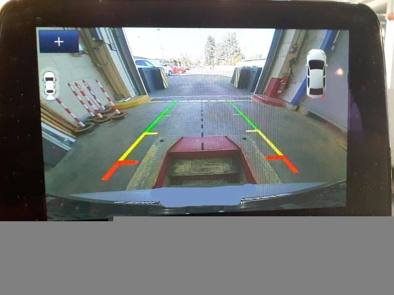 Vue caméra de recul du Ford Kuga gris Solar 2024 avec lignes de guidage colorées et affichage d'aide au stationnement.