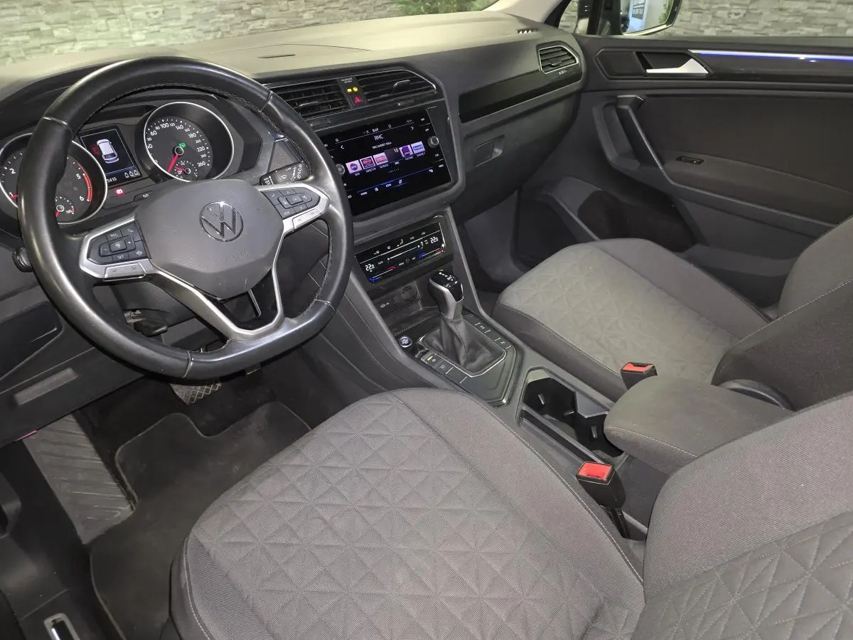 Vue intérieure avant droite du Volkswagen Tiguan 2022, sièges tissu gris et tableau de bord avec écran tactile.