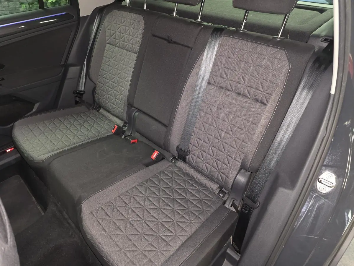 Vue intérieure sur la banquette arrière du Volkswagen Tiguan 2022, tissu gris à motif géométrique, ceinture noire visible.