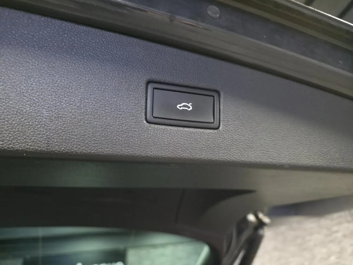 Bouton d'ouverture électrique du coffre sur le panneau intérieur gris du hayon d'un Volkswagen Tiguan 2022.