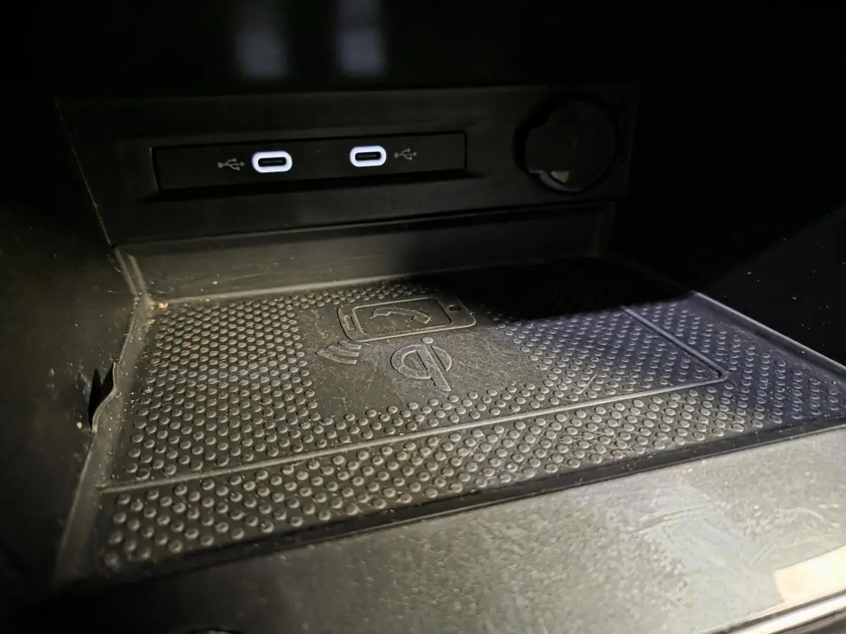 Gros plan sur la zone de recharge sans fil et les deux ports USB-C du Volkswagen Tiguan gris, intérieur noir.