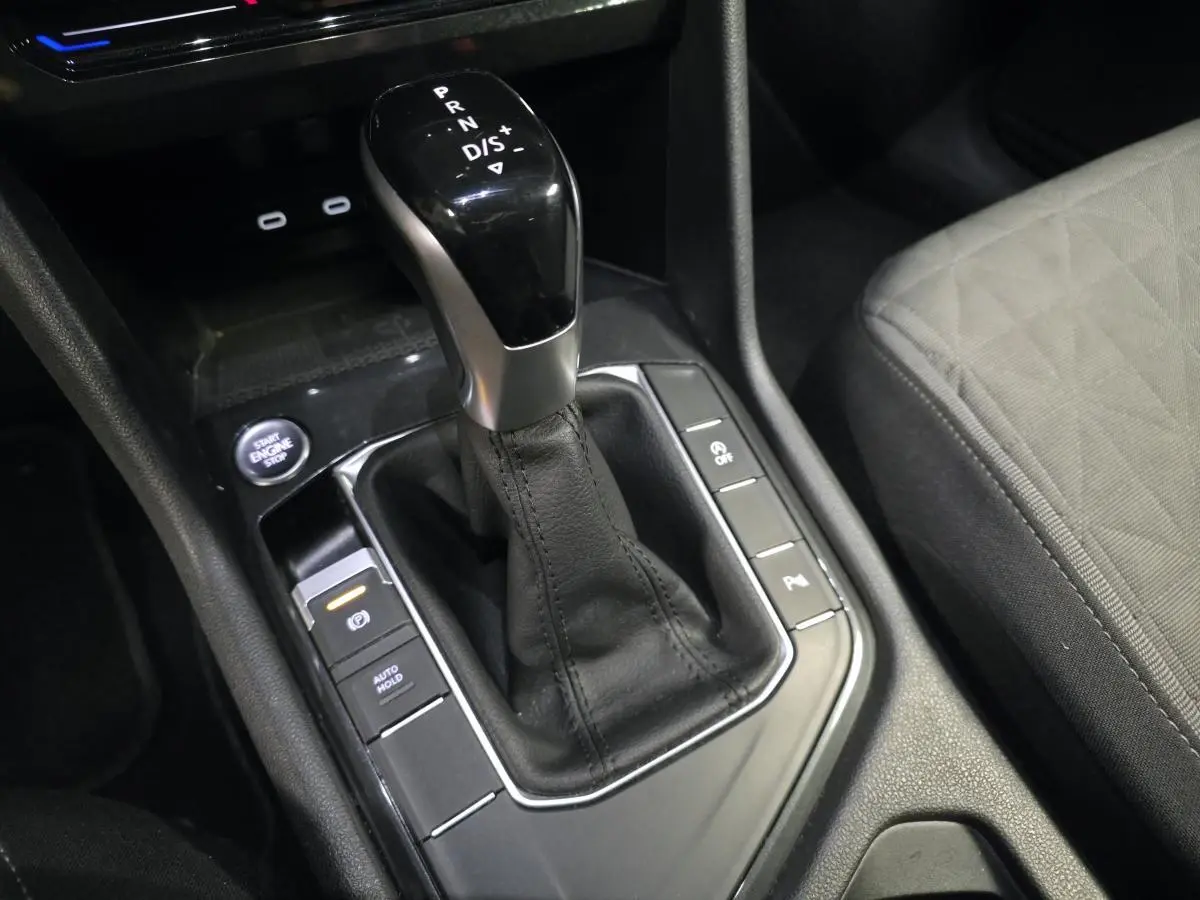 Gros plan sur la console centrale du Volkswagen Tiguan 2022, levier de boîte auto noir et siège tissu gris visible.