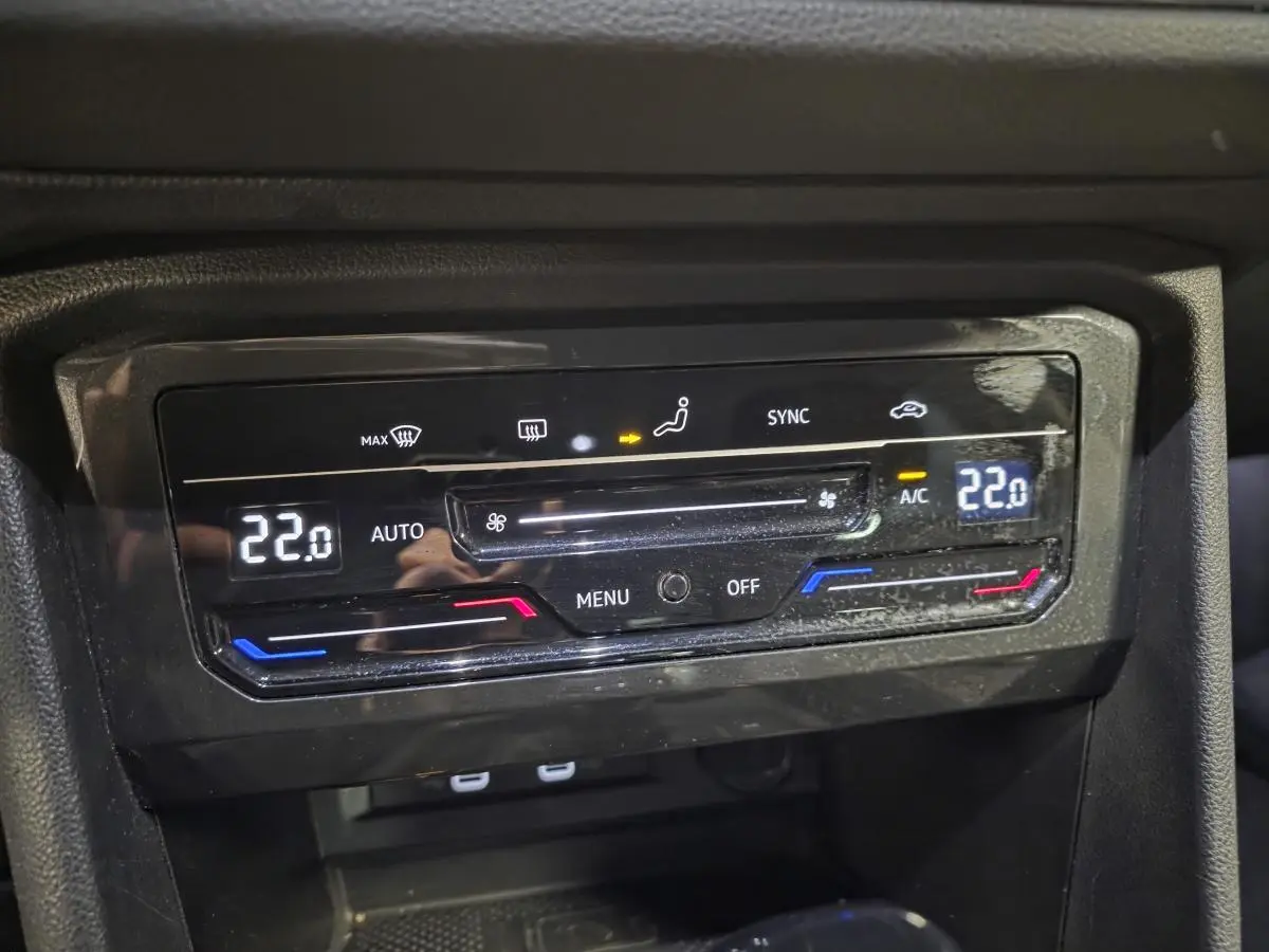 Gros plan sur la commande de climatisation automatique tri-zone du Volkswagen Tiguan gris, affichant 22°C.