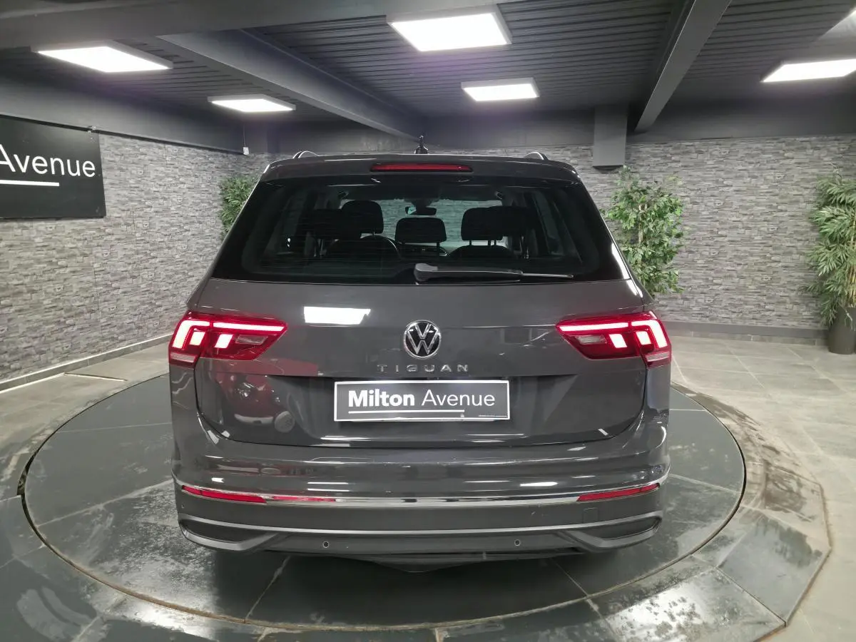 Vue arrière d'un Volkswagen Tiguan gris métallisé 2022 avec feux LED allumés dans un showroom.