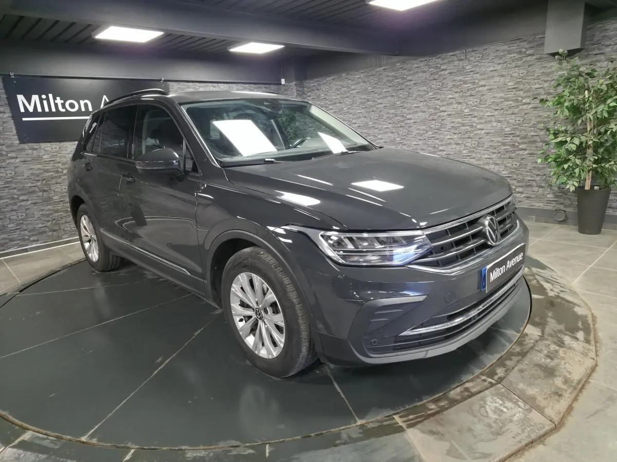 Volkswagen Tiguan gris 3/4 avant droit en intérieur, avec jantes alliage et calandre chromée.
