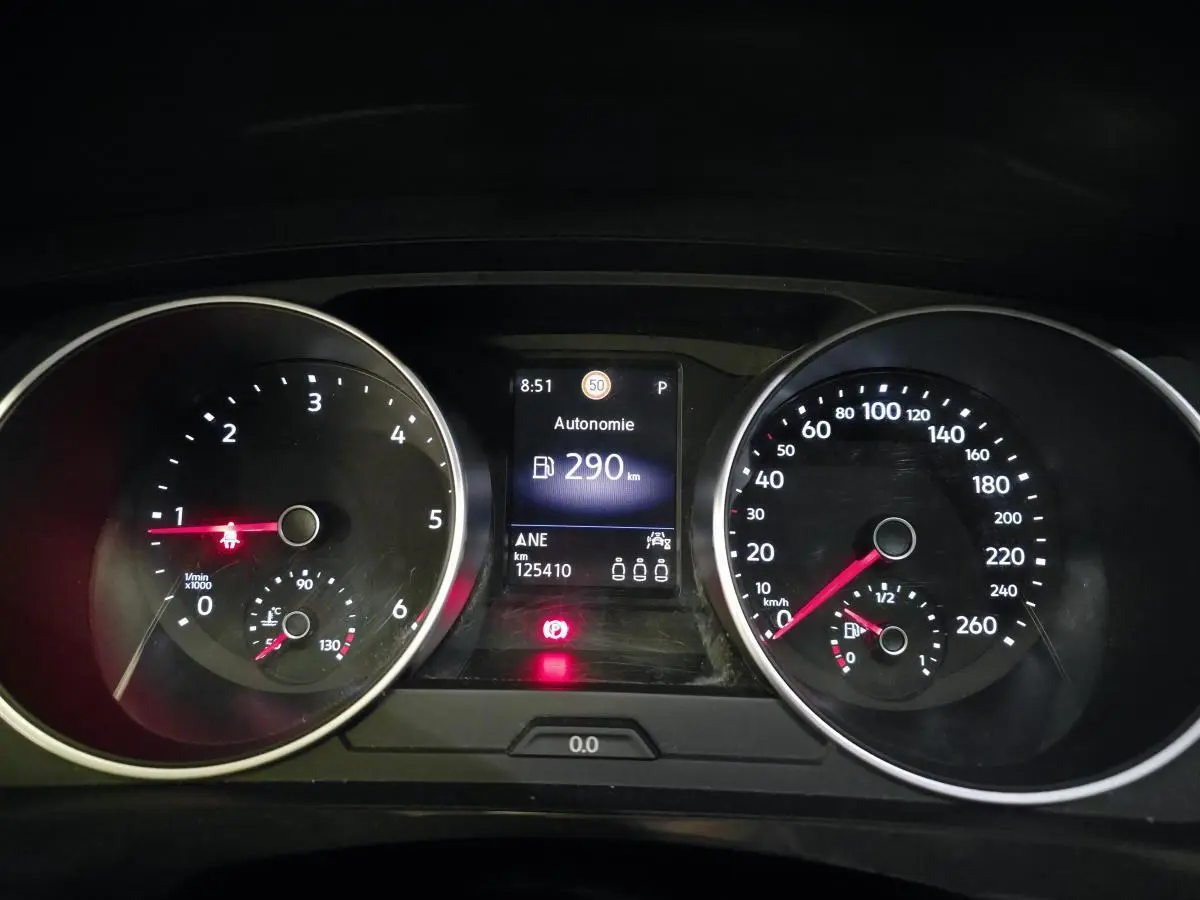 Vue rapprochée du tableau de bord du Volkswagen Tiguan gris, affichant l'autonomie et les compteurs analogiques.