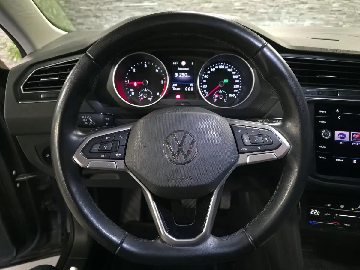 Vue rapprochée du volant cuir multifonctions noir et du tableau de bord digital du Volkswagen Tiguan gris 2022.