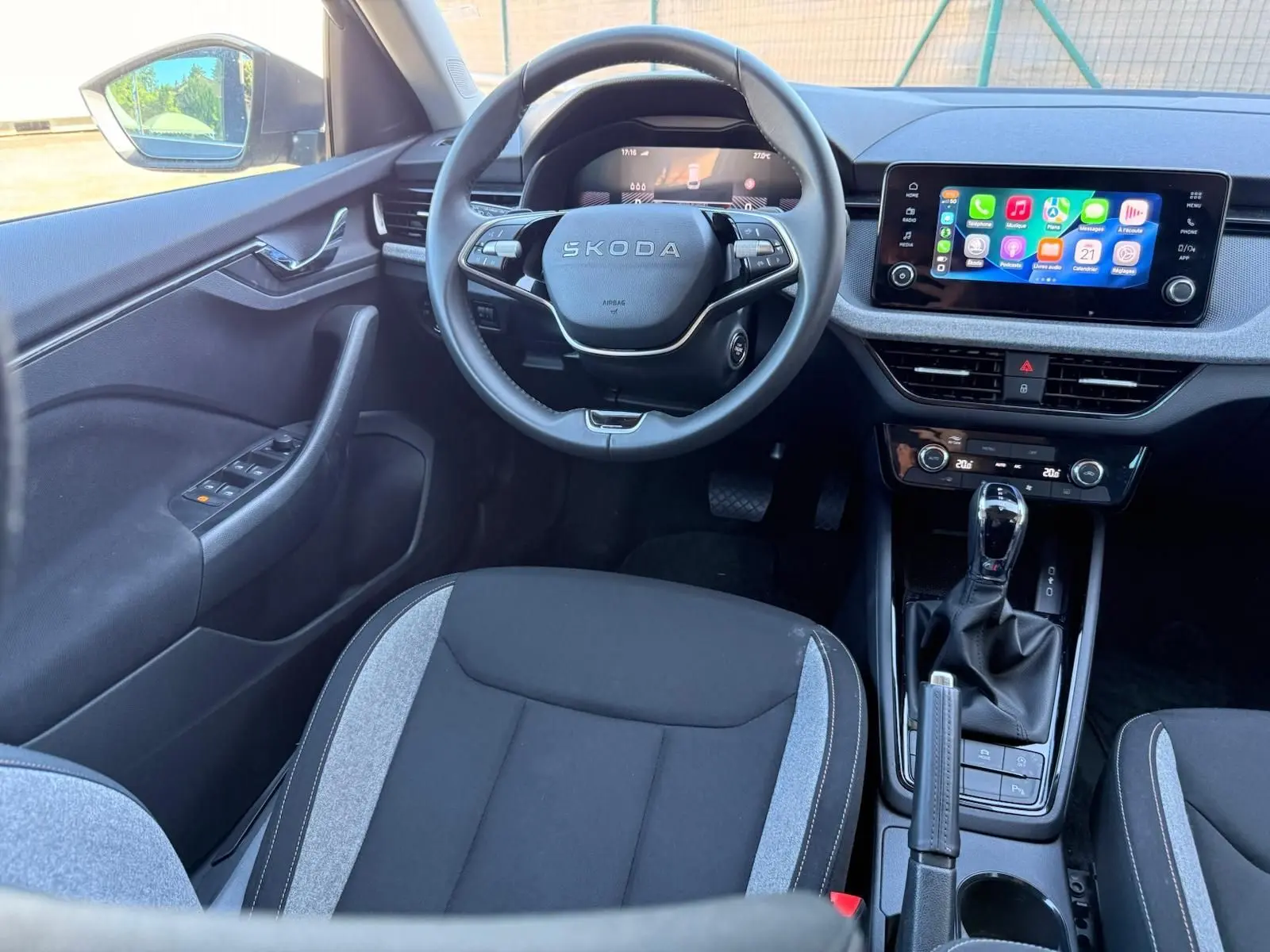 Vue intérieure avant de la Skoda Scala 2025 gris graphite, volant multifonction et écran tactile central avec connectivité smartphone.