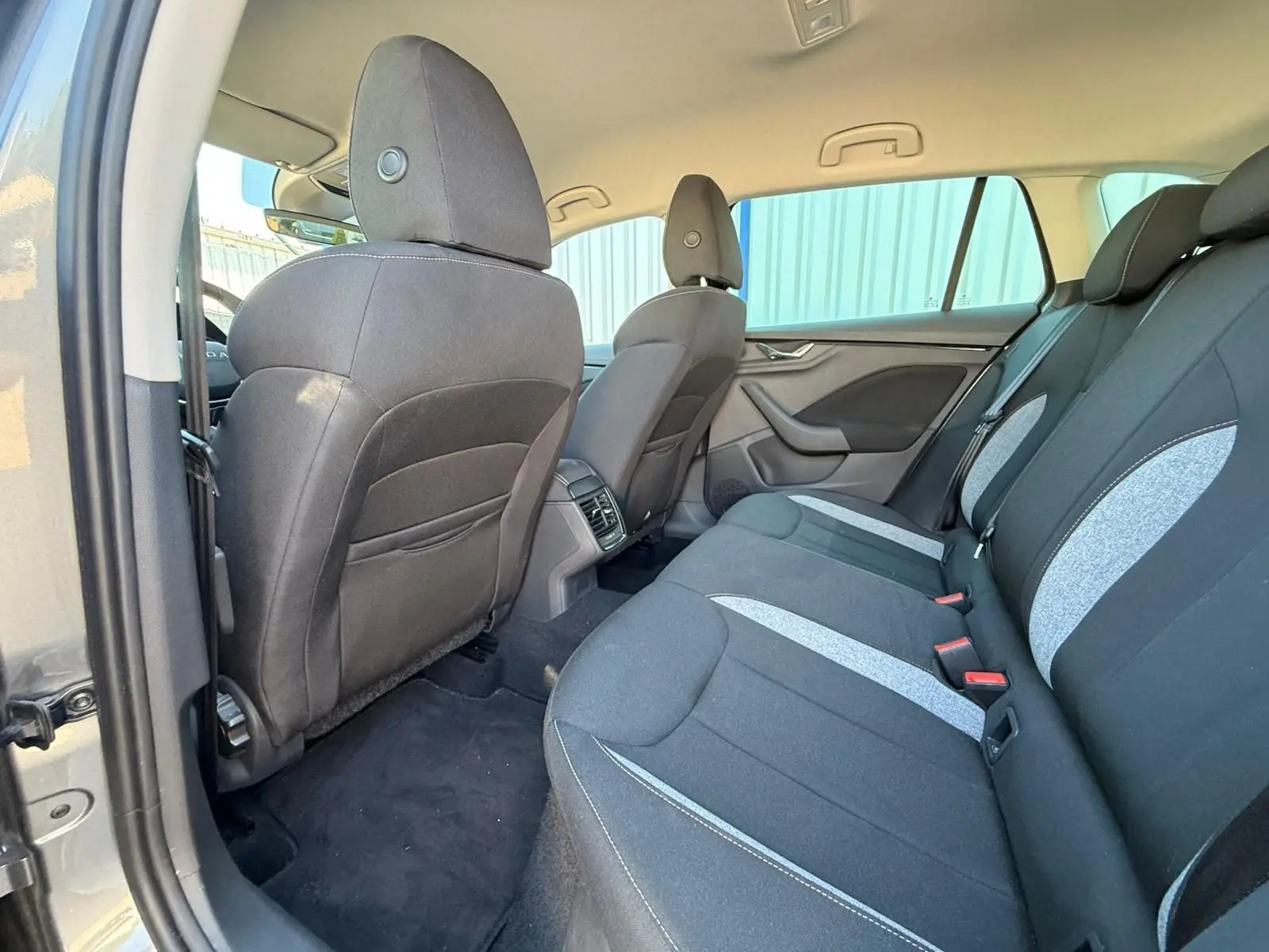 Vue intérieure arrière côté gauche de la Skoda Scala 2025 gris graphite, montrant les sièges tissu bicolores et les aérateurs centraux.