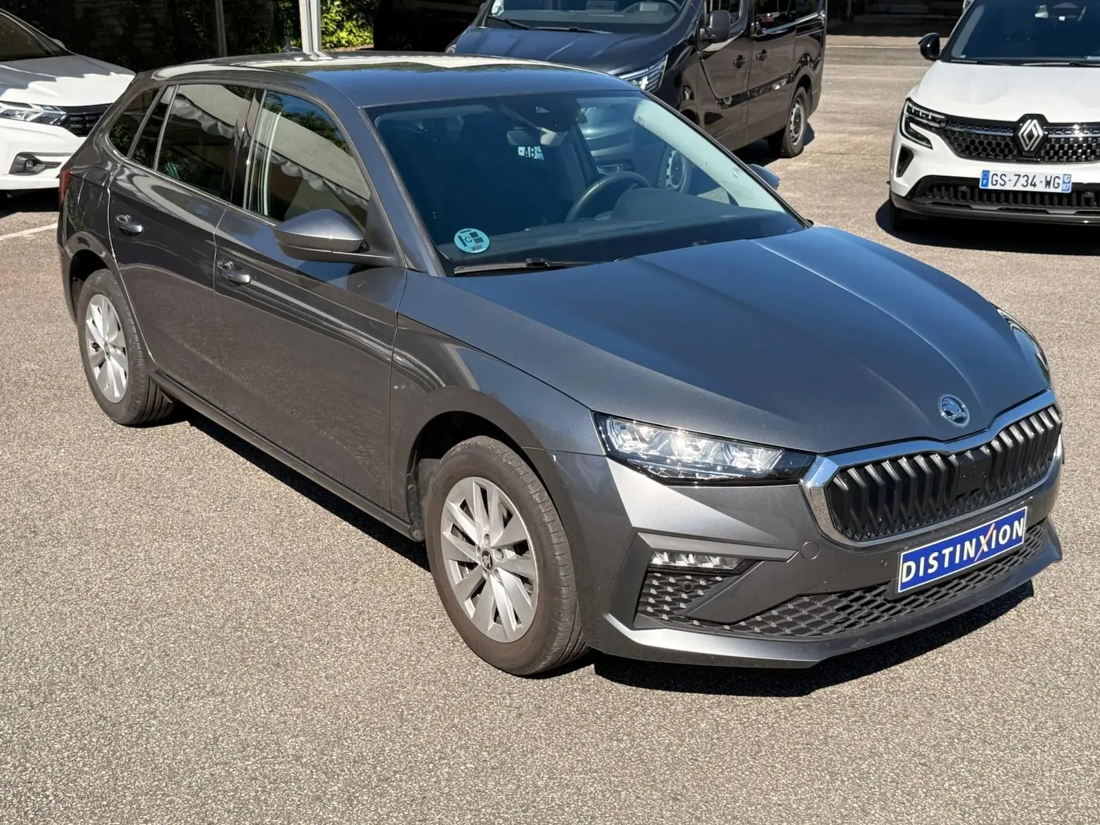 Vue 3/4 avant gauche d'une Skoda Scala gris graphite 2025 avec calandre distinctive et phares LED allumés.