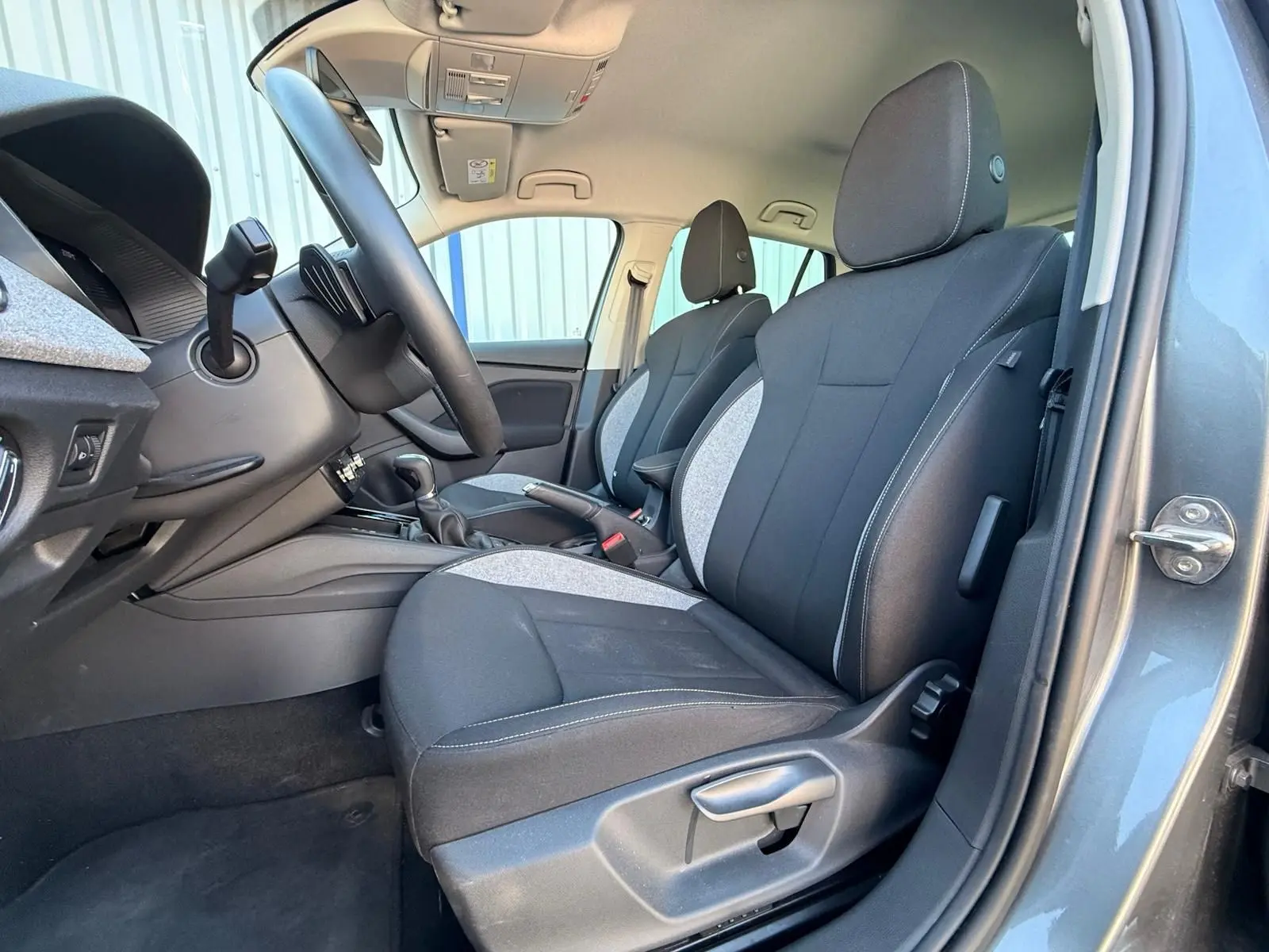 Vue intérieure côté conducteur de la Skoda Scala gris graphite 2025, montrant les sièges avant en tissu bicolore noir et gris.