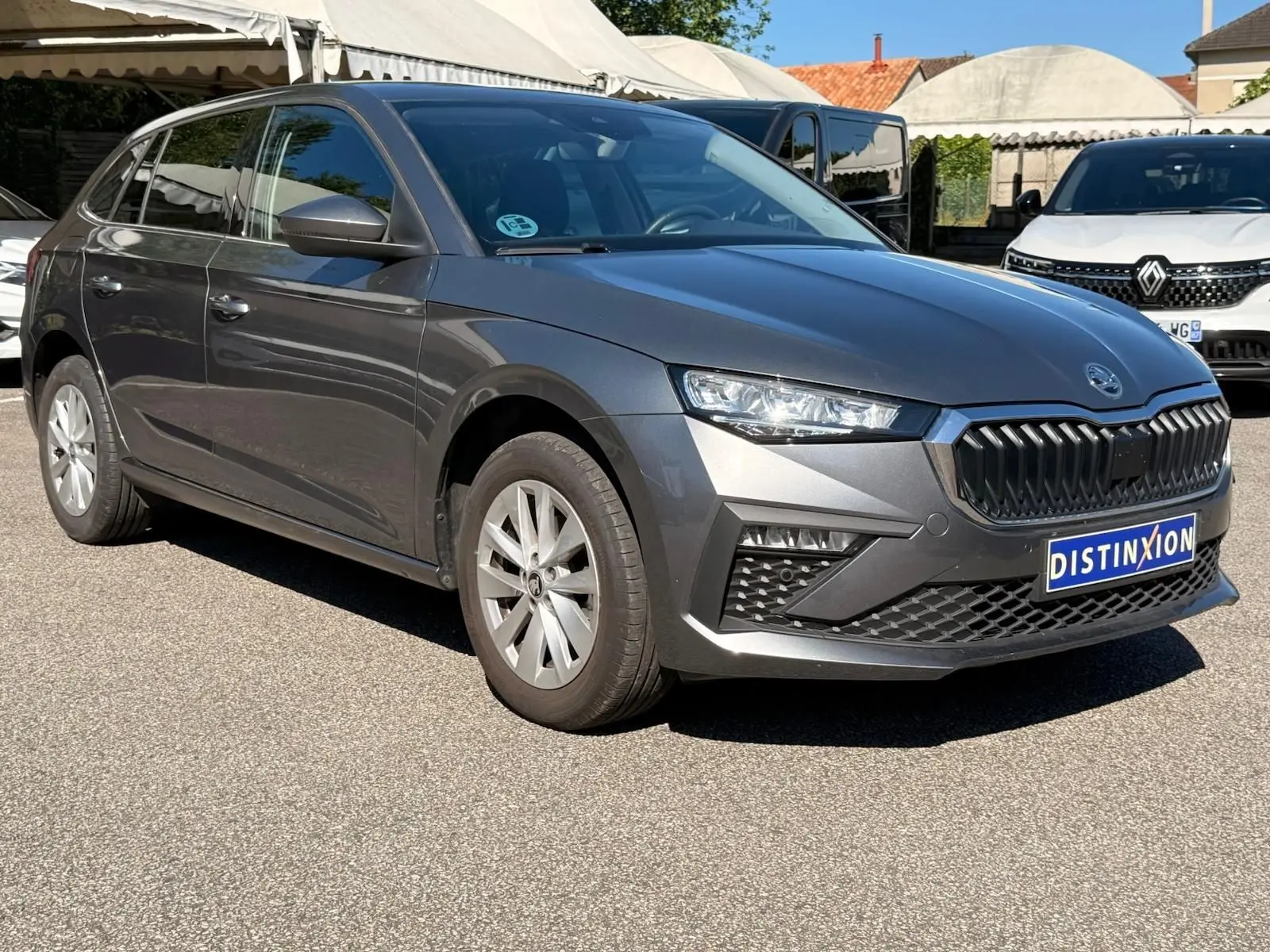 Vue 3/4 avant droite d'une Skoda Scala gris graphite 2025 avec calandre noire et jantes argentées.
