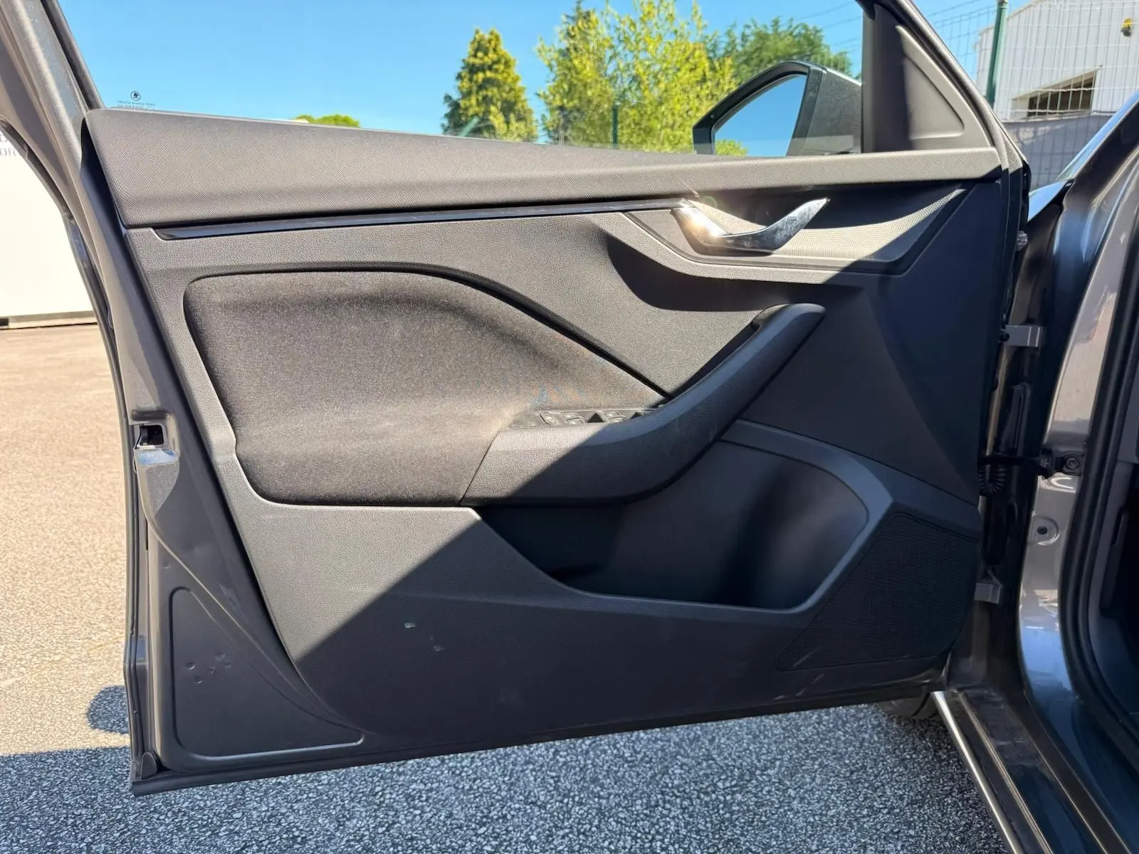 Vue rapprochée de la porte avant gauche gris graphite d’une Skoda Scala 2025, avec poignée chromée et commandes de vitres.