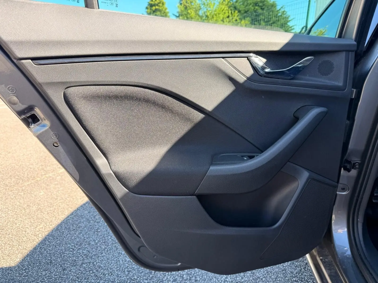Vue de profil intérieur de la porte arrière gauche gris graphite du Skoda Scala 2025 avec poignée et haut-parleur intégrés.