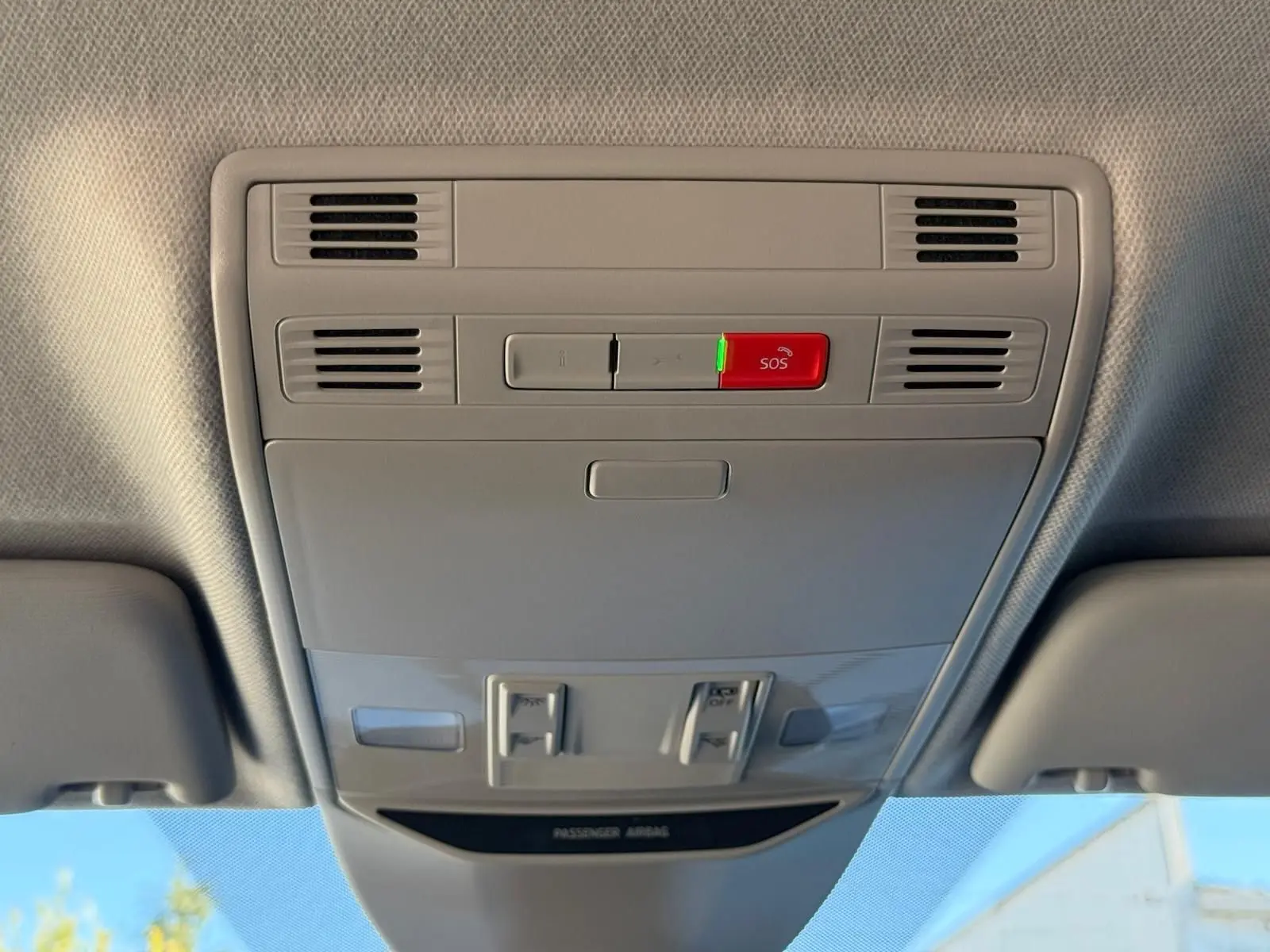Plafonnier intérieur gris clair avec bouton SOS rouge et aérateurs, vue en contre-plongée depuis l'habitacle.