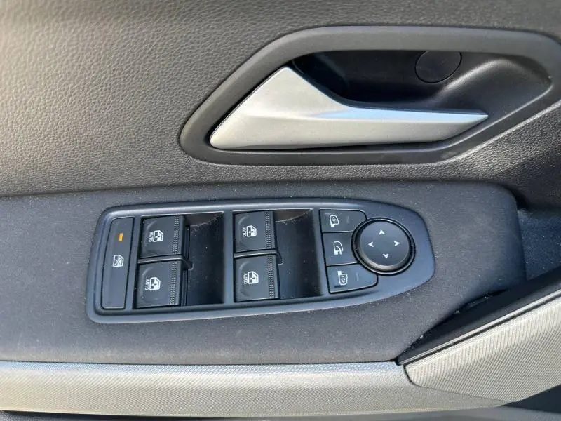 Gros plan sur la commande des vitres électriques et la poignée intérieure grise du côté gauche d’une Dacia Bigster gris schiste.