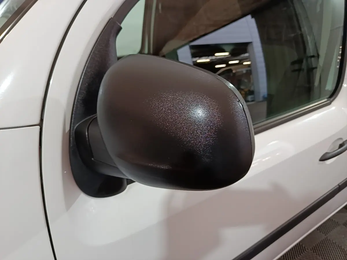 Rétroviseur noir en gros plan côté conducteur du Renault Kangoo blanc, vue latérale rapprochée.