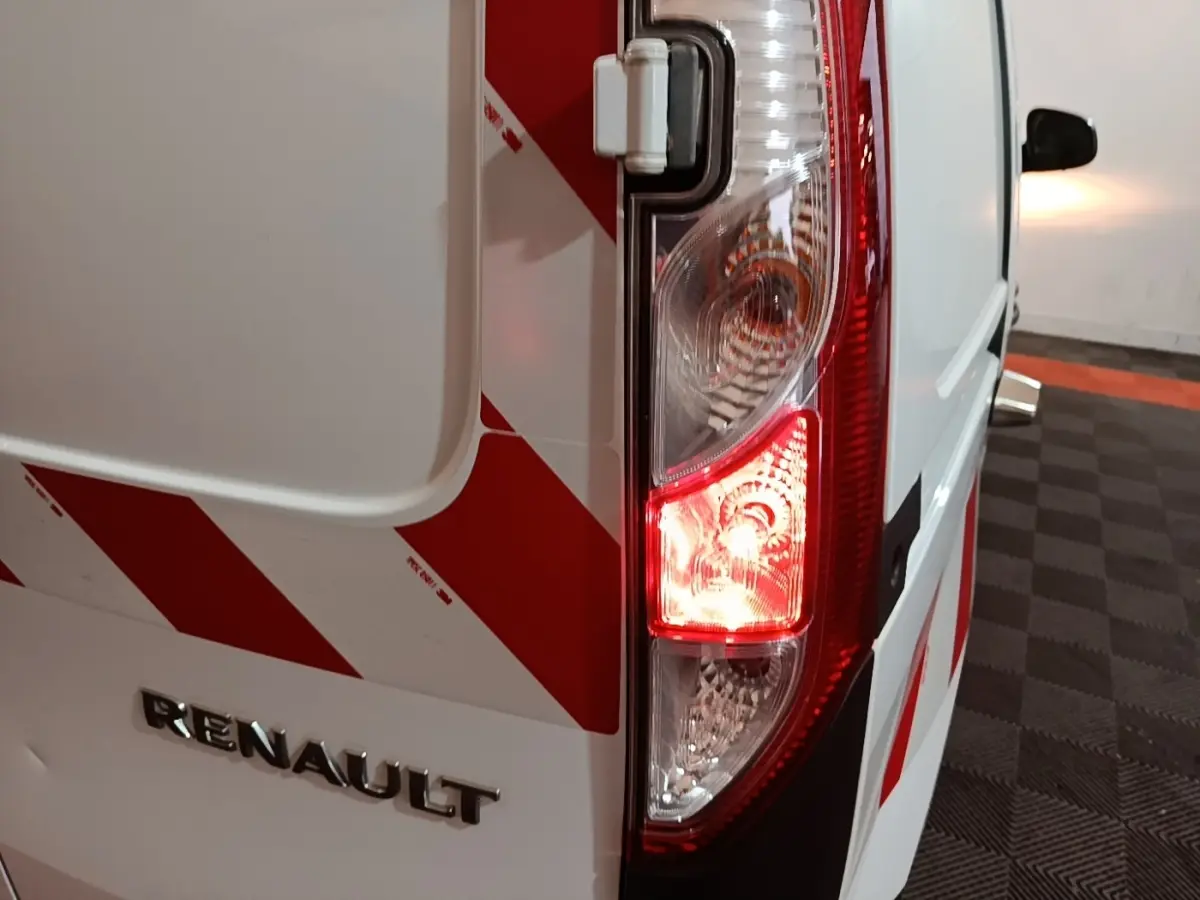 Gros plan sur le feu arrière droit d’un Renault Kangoo blanc avec marquages rouges en diagonale, vue arrière côté droit.