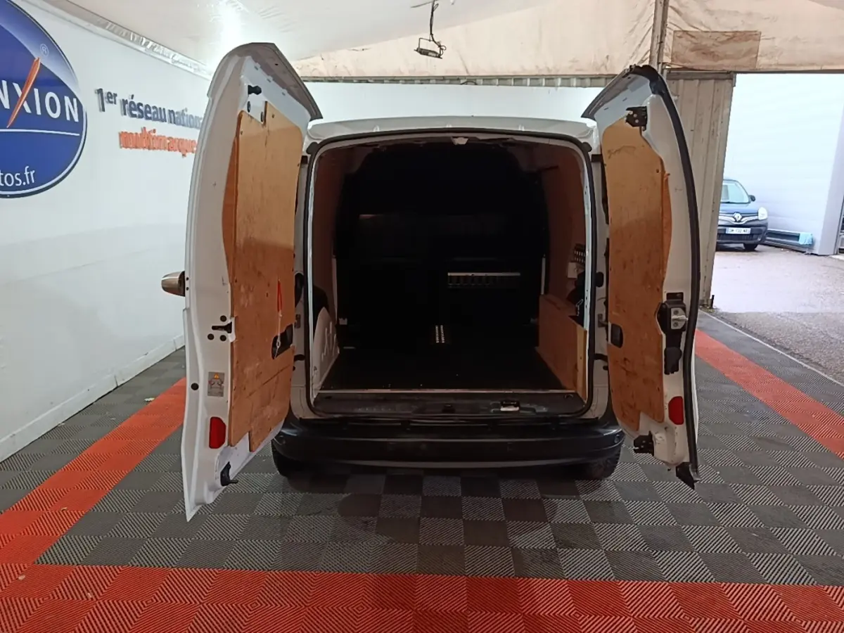 Vue arrière du Renault Kangoo blanc 2020 avec portes arrière ouvertes montrant l'espace de chargement vide et cloison bois.