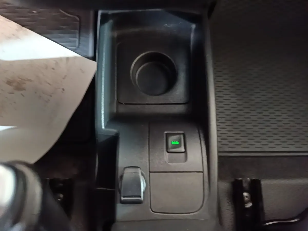 Gros plan sur la console centrale noire du Renault Kangoo blanc, avec bouton ECO éclairé en vert.